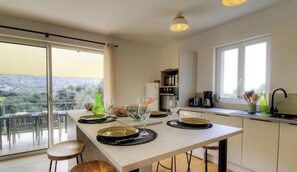 Eine moderne Küche mit Essbereich, großen Fenstern und Blick ins Freie.