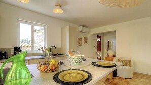 A modern kitchen with a dining area, a large window, and an air conditioning unit. - Petrabianca - CARGESE (CARGESE)