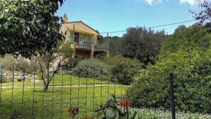 A house with a balcony, surrounded by a fenced garden with various plants and flowers. - Petrabianca - CARGESE (CARGESE)