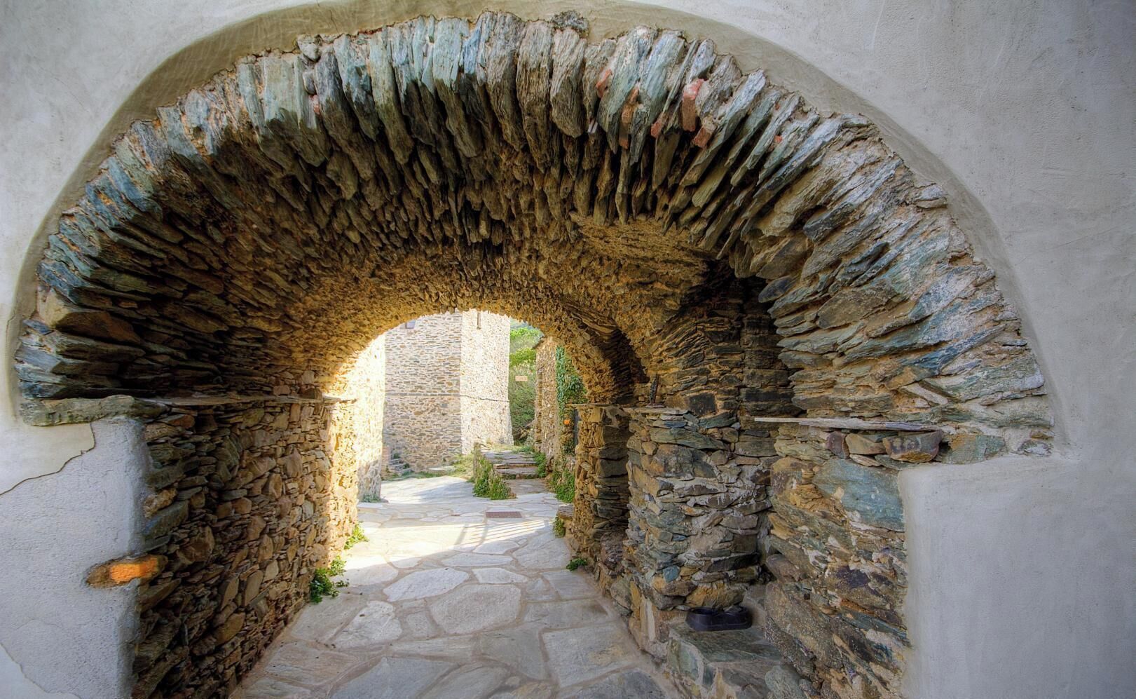 An arched stone doorway leading to a stone pathway.