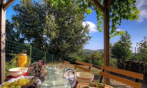 An outdoor dining area with a wooden bench, a table with a pitcher, bowls, and grapes. - A Casa Di I Ricordi - SISCO (SISCO)