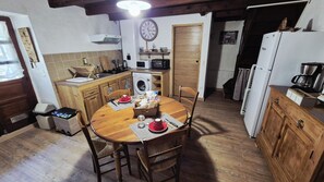 Cocina compacta con armarios de madera, una mesa de comedor con sillas, lavadora, microondas y refrigerador.
