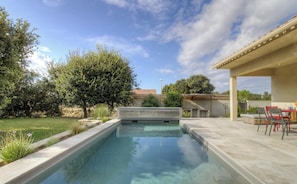 Ein Schwimmbad mit einer Terrassenanlage, einer Pergola und Blick auf die umliegende Landschaft.