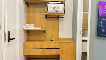 A compact room with a wooden vanity, a towel rack, and a small shelf.