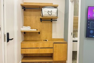 Habitación pequeña con tocador de madera, perchero y estante.