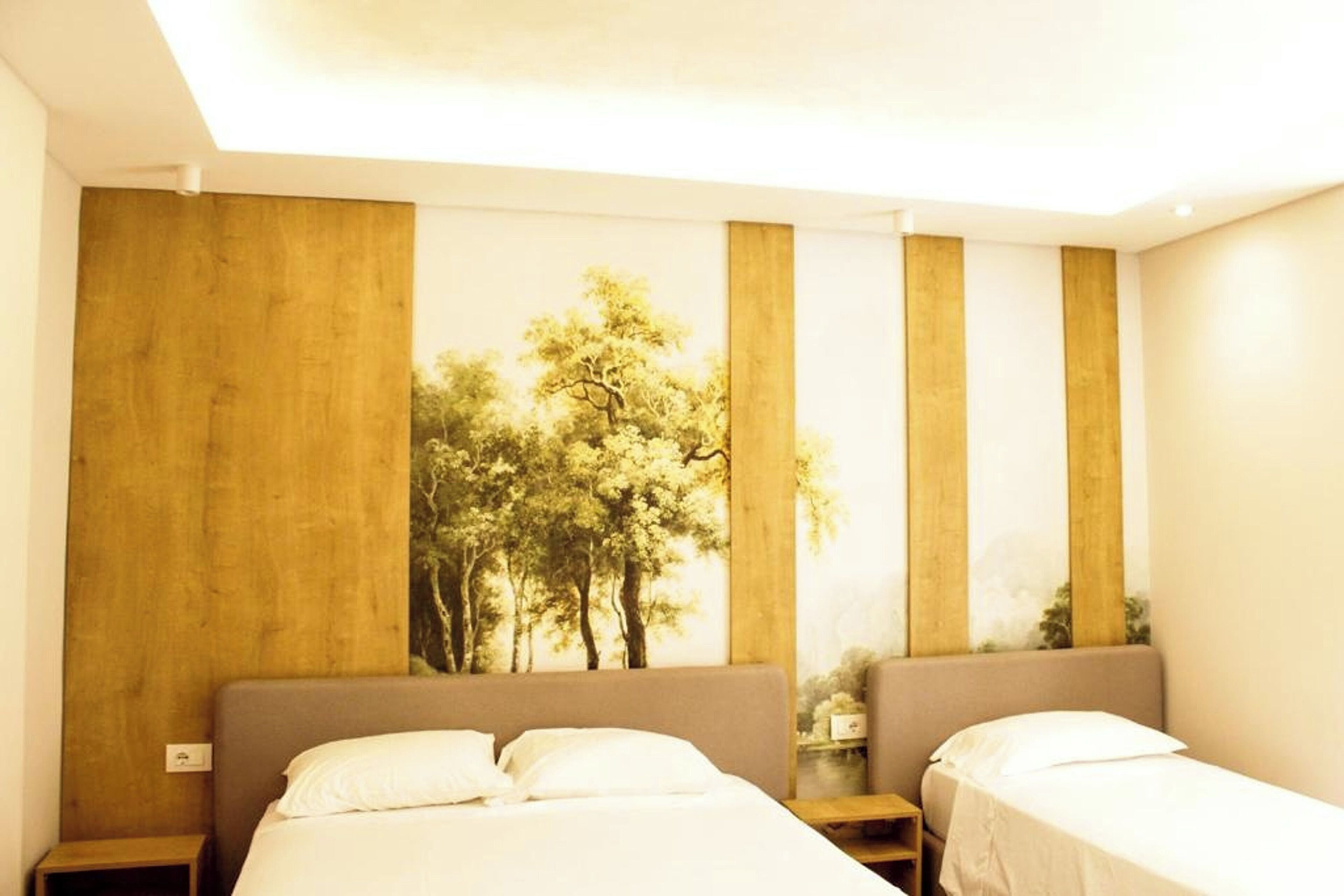 Habitación de hotel con dos camas, una pared decorativa de madera y una pintura de árboles.