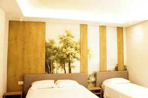 Habitación de hotel con dos camas, una pared decorativa de madera y una pintura de árboles.