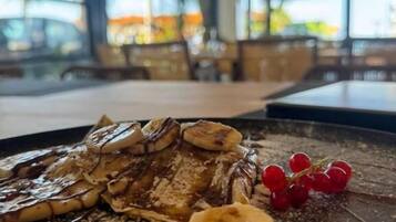 Une assiette de dessert avec de la sauce au chocolat, des bananes et des raisins, posée sur une table dans un restaurant.