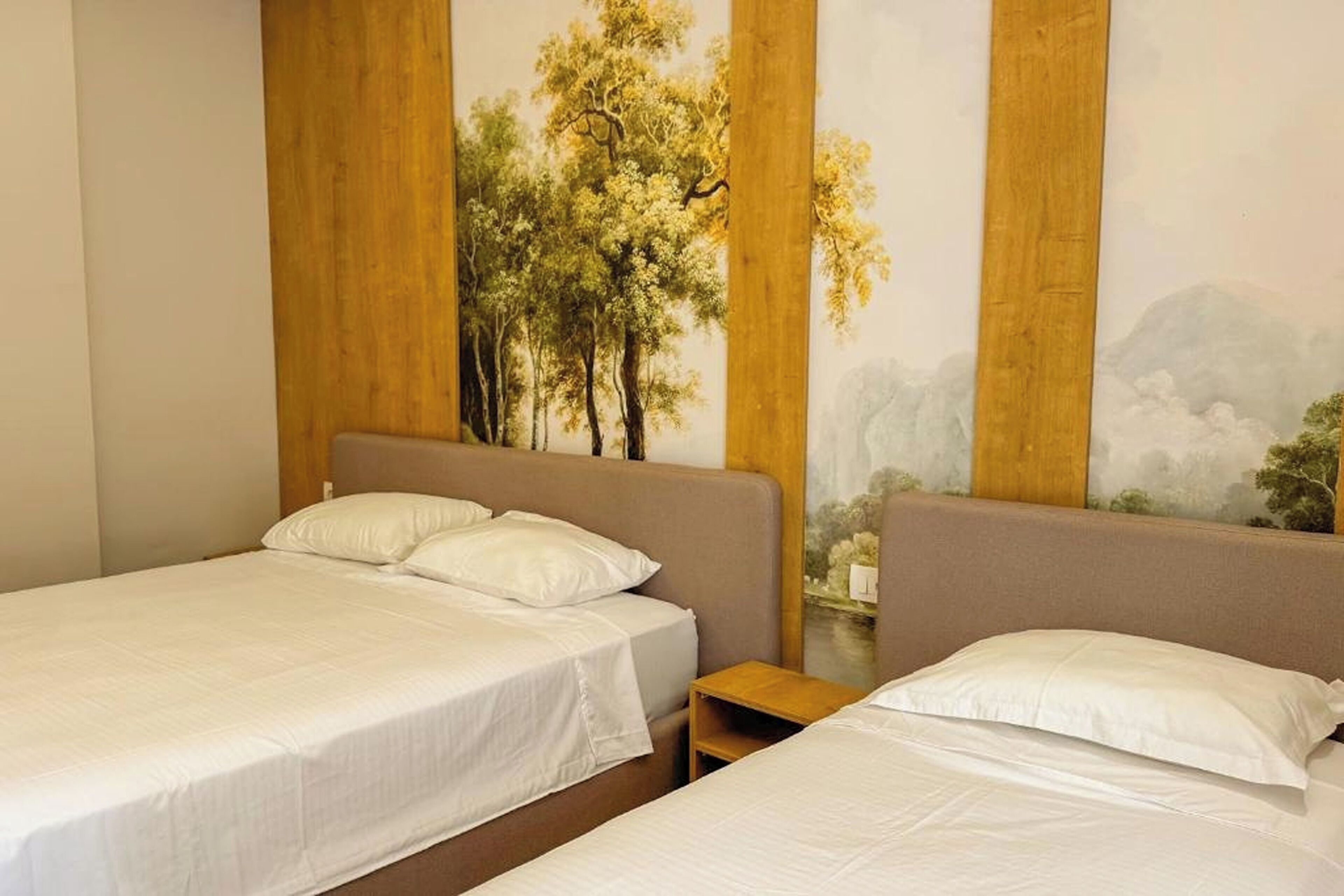 Habitación de hotel con dos camas, cada una con ropa blanca y almohadas. La habitación presenta un mural grande que muestra un paisaje forestal.