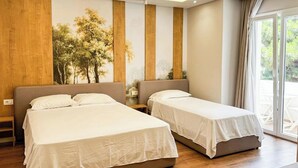 Habitación de hotel con dos camas, un ventanal grande y vistas a zonas verdes.