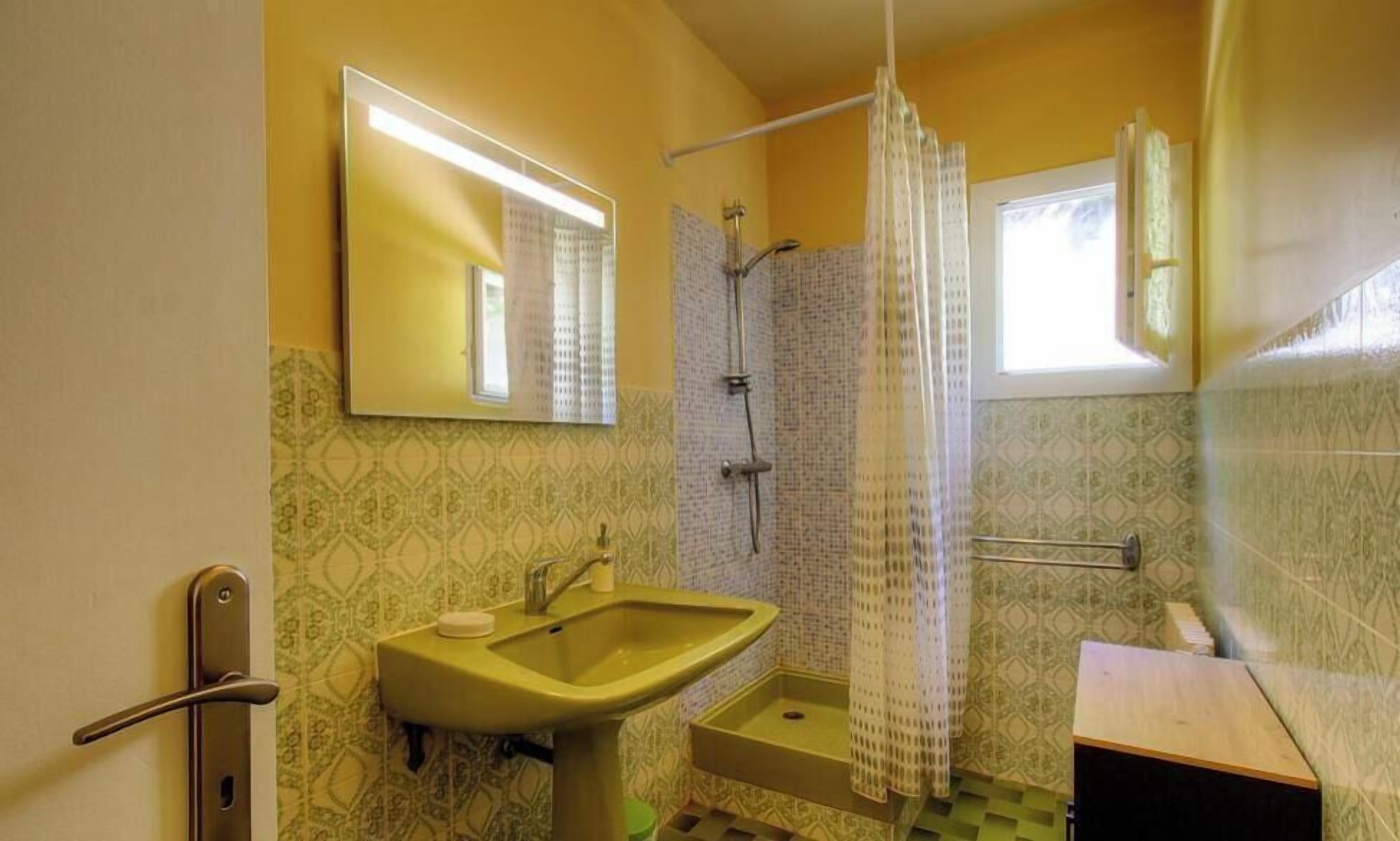 Baño con lavabo, espejo, ducha y paredes con diseño.