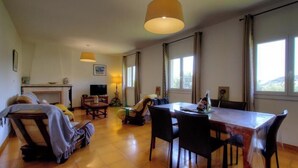 Ein geräumiger Raum mit Esstisch, Stühlen, einer Couch und einem großen Fenster für natürliches Licht.