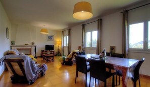 Ein geräumiger Raum mit Esstisch, Stühlen, einer Couch und einem großen Fenster für natürliches Licht.