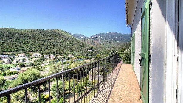Ein Balkon mit Blick auf eine gebirgige Landschaft und ein Dorf darunter.