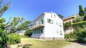 Ein zweistöckiges Gebäude mit flachem Dach, grünen Fensterläden und einem Steinfundament.