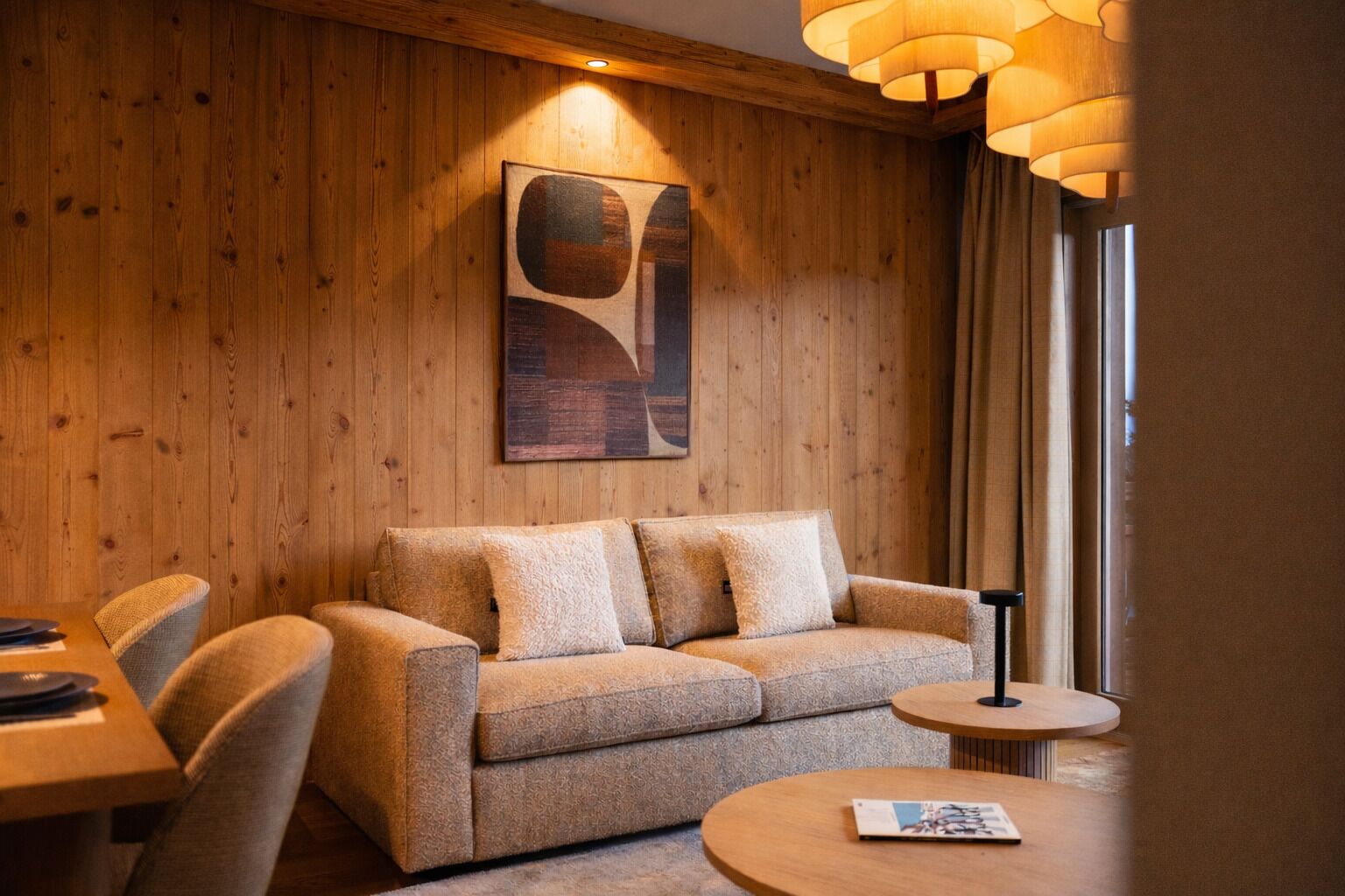 Ein gemütliches Zimmer mit einer Holzwand, einem Sofa, einem kleinen Tisch und einer Lampe.