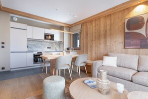 A modern kitchen with white cabinets, a marble backsplash, and a dining area with a wooden table and chairs.