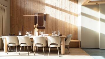 A dining area with a wooden wall, a hanging light fixture, and a table set for four.