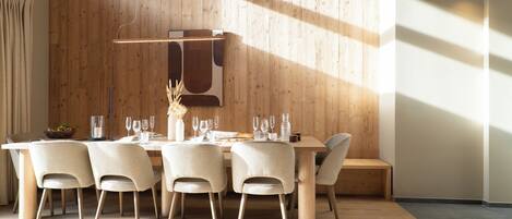 Un coin repas avec un mur en bois, un luminaire suspendu et une table dressée pour quatre personnes.
