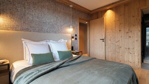 Une chambre à coucher avec un lit, des oreillers, une table de chevet, un mur orné d’un motif texturé et une porte en bois.