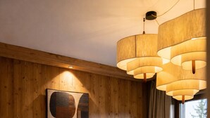 A modern living room with a wooden wall, a sofa, a round coffee table, and a large window. - Résidence Barma Courchevel (Courchevel)