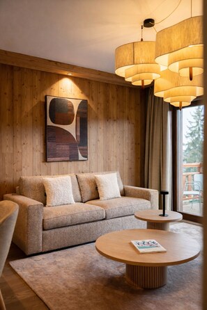 A modern living room with a wooden wall, a sofa, a round coffee table, and a large window.