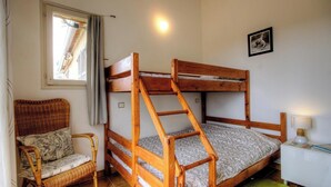 A bunk bed with a ladder, a wicker chair, a small table with a lamp, and a window with curtains. - In Chjusella - BELGODERE (BELGODERE)