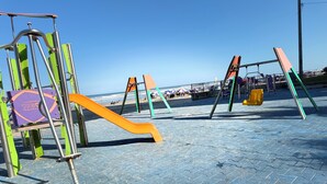 Um parquinho infantil com escorrega, balanços e uma estrutura de escalada.