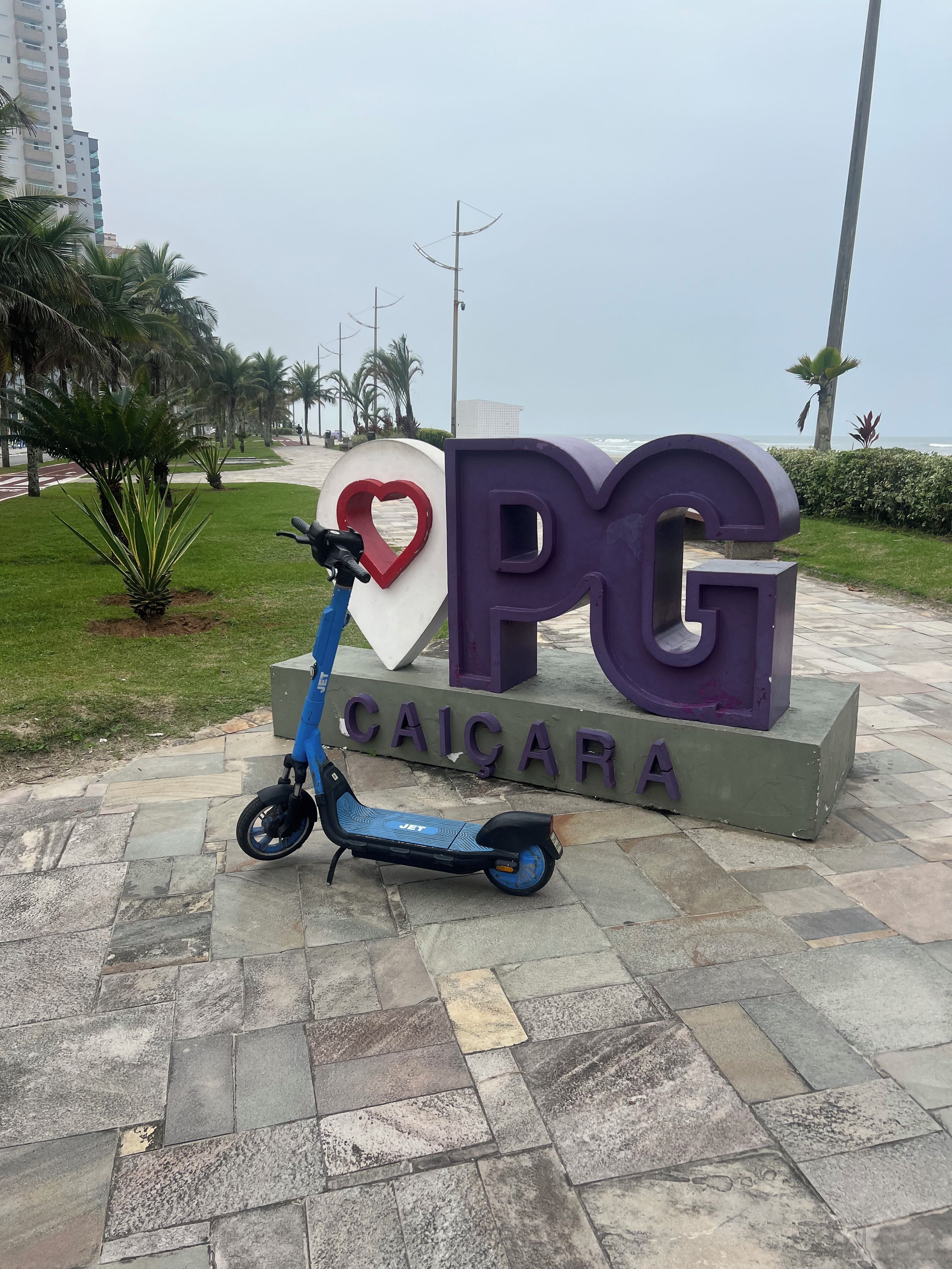 A blue electric scooter parked in front of a sign with 'PG' and 'CAICARA' on it.