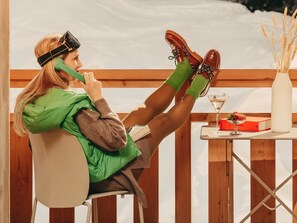 Eine Person sitzt an einem Tisch mit einem Buch, einem Martini-Glas und einer Vase mit Schilf.