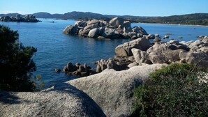 A coastal landscape with large boulders, calm water, and distant hills. - Rocca Rossa - PORTO VECCHIO (PORTO VECCHIO)