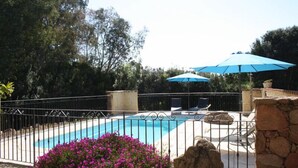 A swimming pool with a fence, a blue umbrella, and surrounding greenery. - Rocca Rossa - PORTO VECCHIO (PORTO VECCHIO)