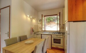 Eine kleine Küche mit Esstisch, Herd, Backofen und Kühlschrank.