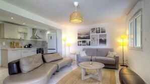 A modern living room with a sofa, a coffee table, and a dining area with a kitchen in the background. - Casa S - Carlu - TRALONCA (TRALONCA)