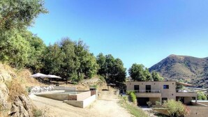 A modern building with a flat roof and a small balcony, surrounded by trees and a hillside. - Casa S - Carlu - TRALONCA (TRALONCA)
