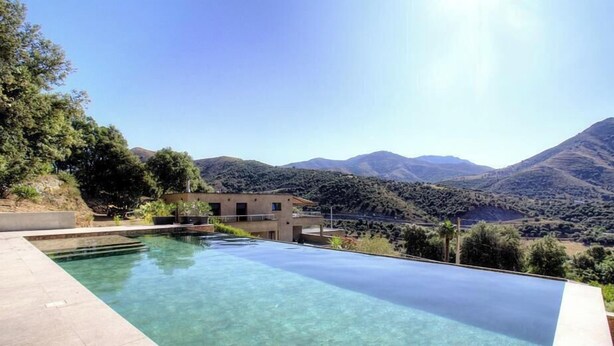 A modern pool with clear water, surrounded by a landscaped area and a building with a flat roof. - Casa S - Carlu - TRALONCA (TRALONCA)