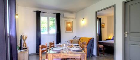 A dining area with a table set for four, a sofa, and a bed in the background.
