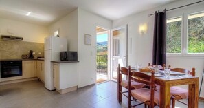 A compact kitchen with a refrigerator, microwave, oven, and a dining area with a table and chairs. - Ponte - SAN NICOLAO - Gîte (SAN NICOLAO)