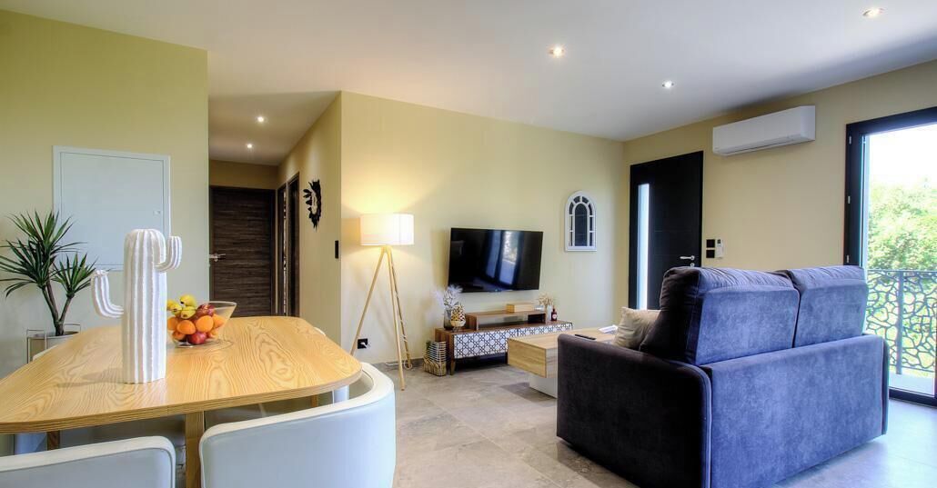 Un salon moderne comprenant un téléviseur, un canapé et un coin repas avec une table et des chaises.
