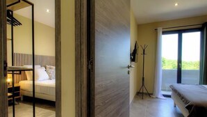 Een hotelkamer met een bed, een bureau, een kapstok en uitzicht op groen.