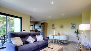 Een moderne woonkamer met een bank, salontafel, eettafel en een keuken op de achtergrond.
