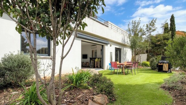 Una casa moderna con un patio, zona de comedor y jardín.
