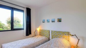 Un dormitorio con dos camas, una ventana y tres pequeños cuadros en la pared.