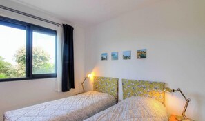 Ein Schlafzimmer mit zwei Betten, einem Fenster und drei kleinen Bildern an der Wand.