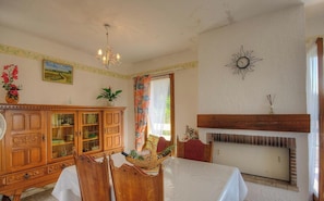 Ein Esszimmer mit Holzschrank, einer Chandelierleuchte, einem Kamin und einem für das Essen gedeckten Tisch.