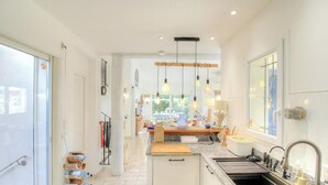 Una cocina moderna con una isla central, iluminación colgante y vista al área de comedor.