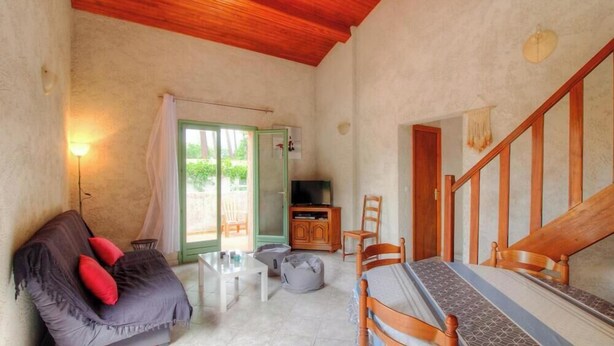 A room with a wooden ceiling, a sofa with red cushions, a television, a dining table with chairs, and a staircase. - The strawberry tree - SAN GAVINO DI CARBINI (SAN GAVINO DI CARBINI)