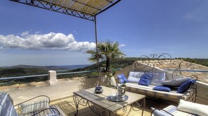 Eine Terrasse im Freien mit Tisch, Stühlen und einer Couch mit Kissen.