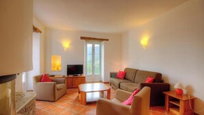 Ein Wohnzimmer mit Sofa, Sesseln, Couchtisch, Fernseher und Kamin.