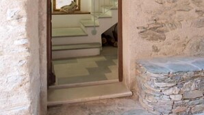 Ein Zimmer mit Steinwänden und einem zur Treppe führenden Durchgang.